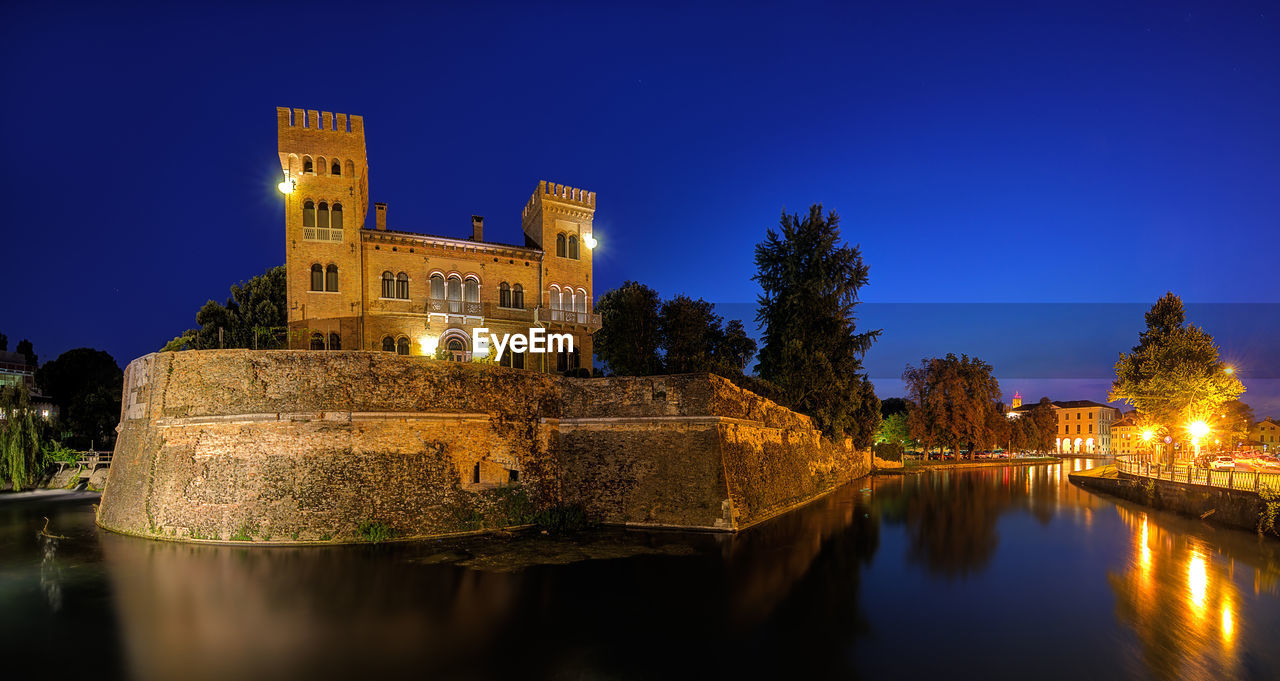 REFLECTION OF ILLUMINATED BUILT STRUCTURE IN WATER AT NIGHT