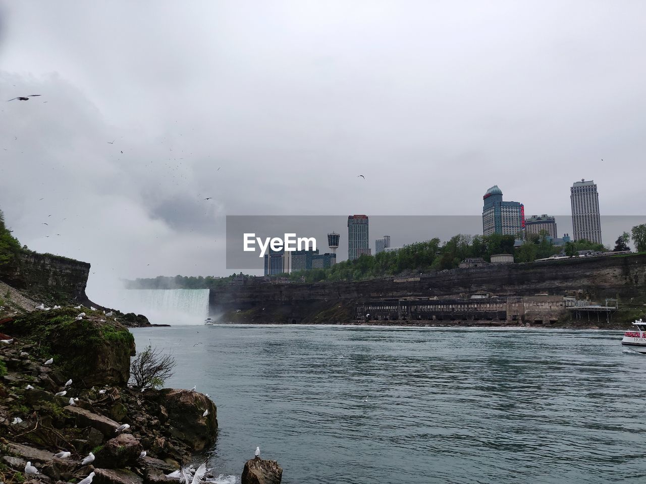Scenic view of river by buildings against sky