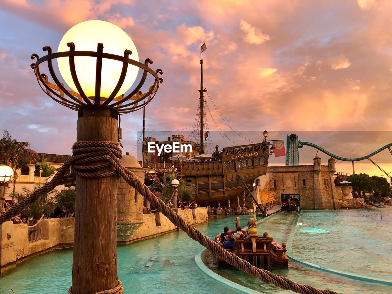 Close-up of illuminated lighting equipment in amusement park during sunset