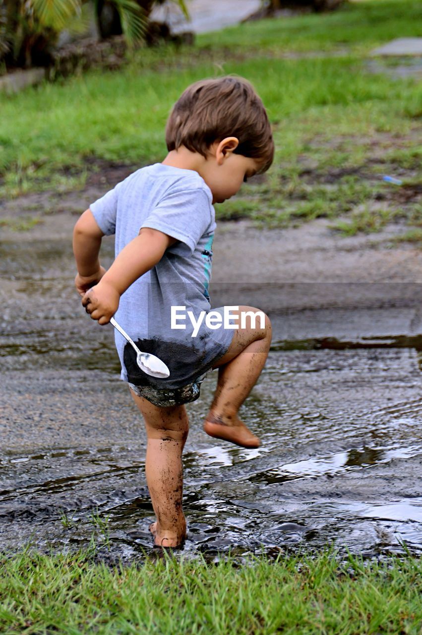 Full length of boy playing in mud