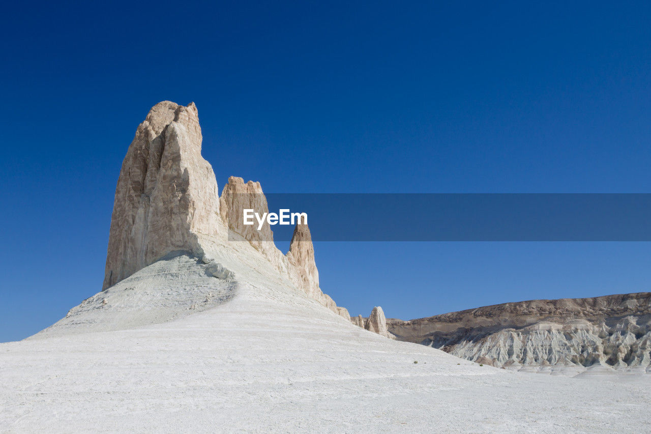 low angle view of rock formations on mountain against clear blue sky