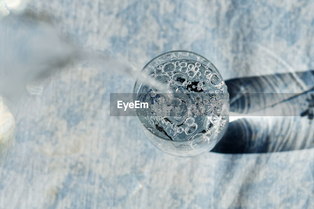 HIGH ANGLE VIEW OF GLASS WITH REFLECTION OF DRINKING WATER