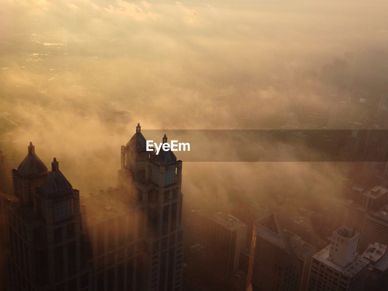 High angle view of castle surrounded by fog during sunset