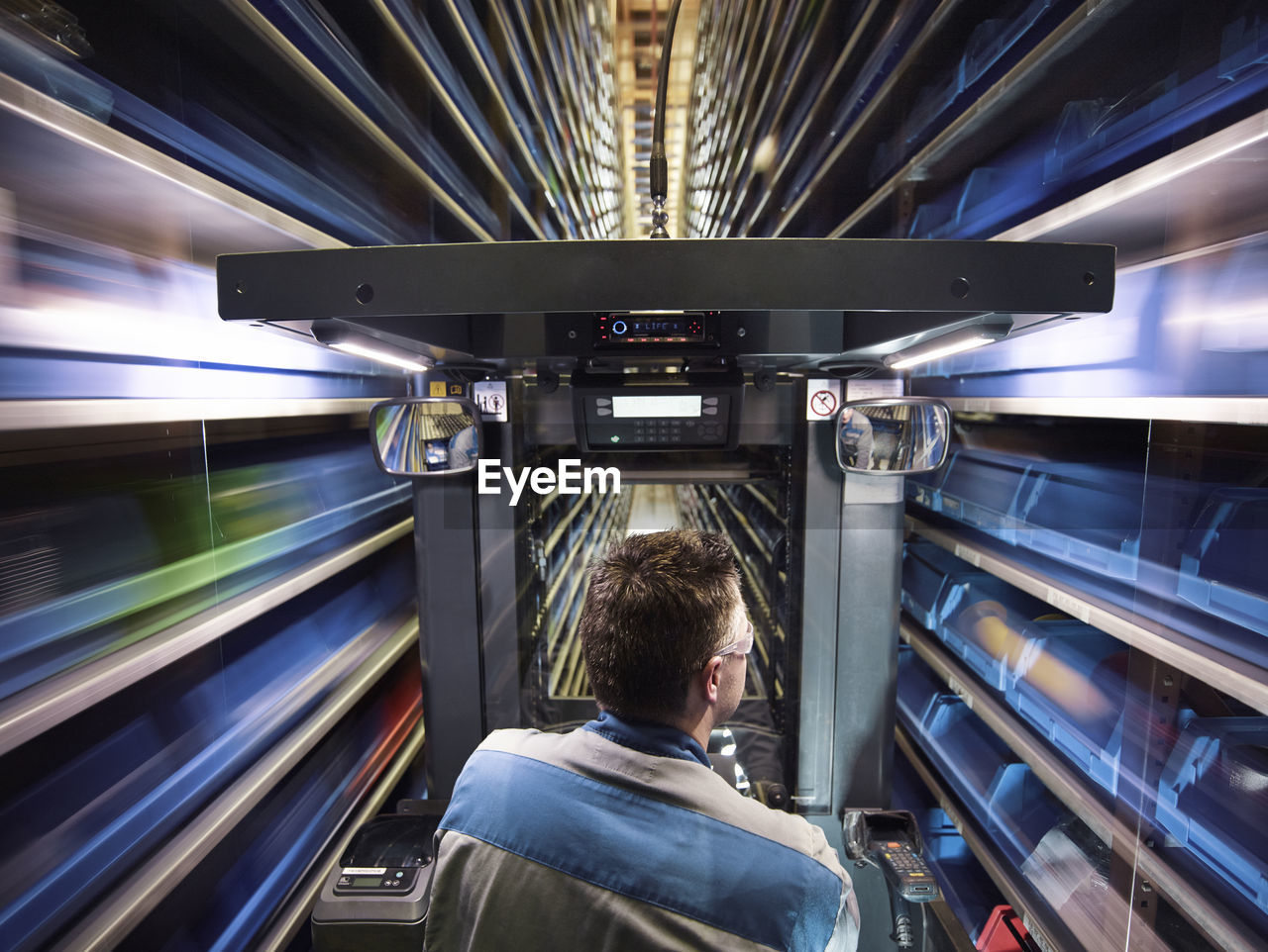 Worker operating high rack in storehouse
