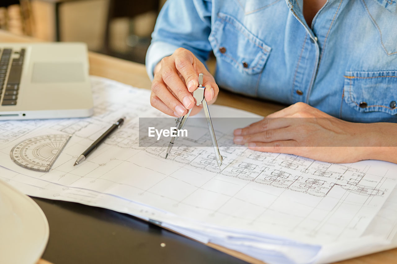 Midsection of architect making blueprint at desk