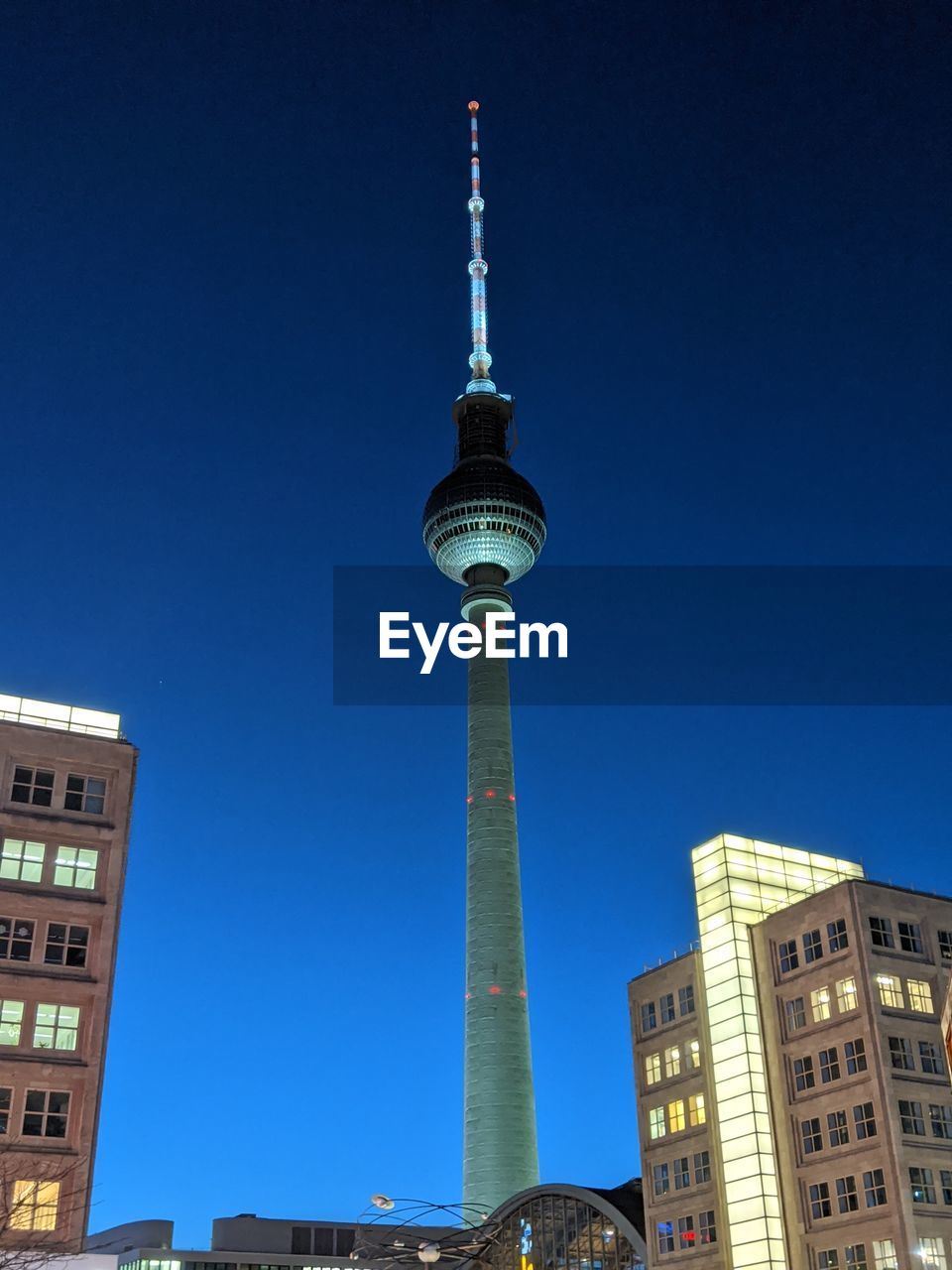 LOW ANGLE VIEW OF COMMUNICATIONS TOWER AND BUILDINGS AGAINST SKY