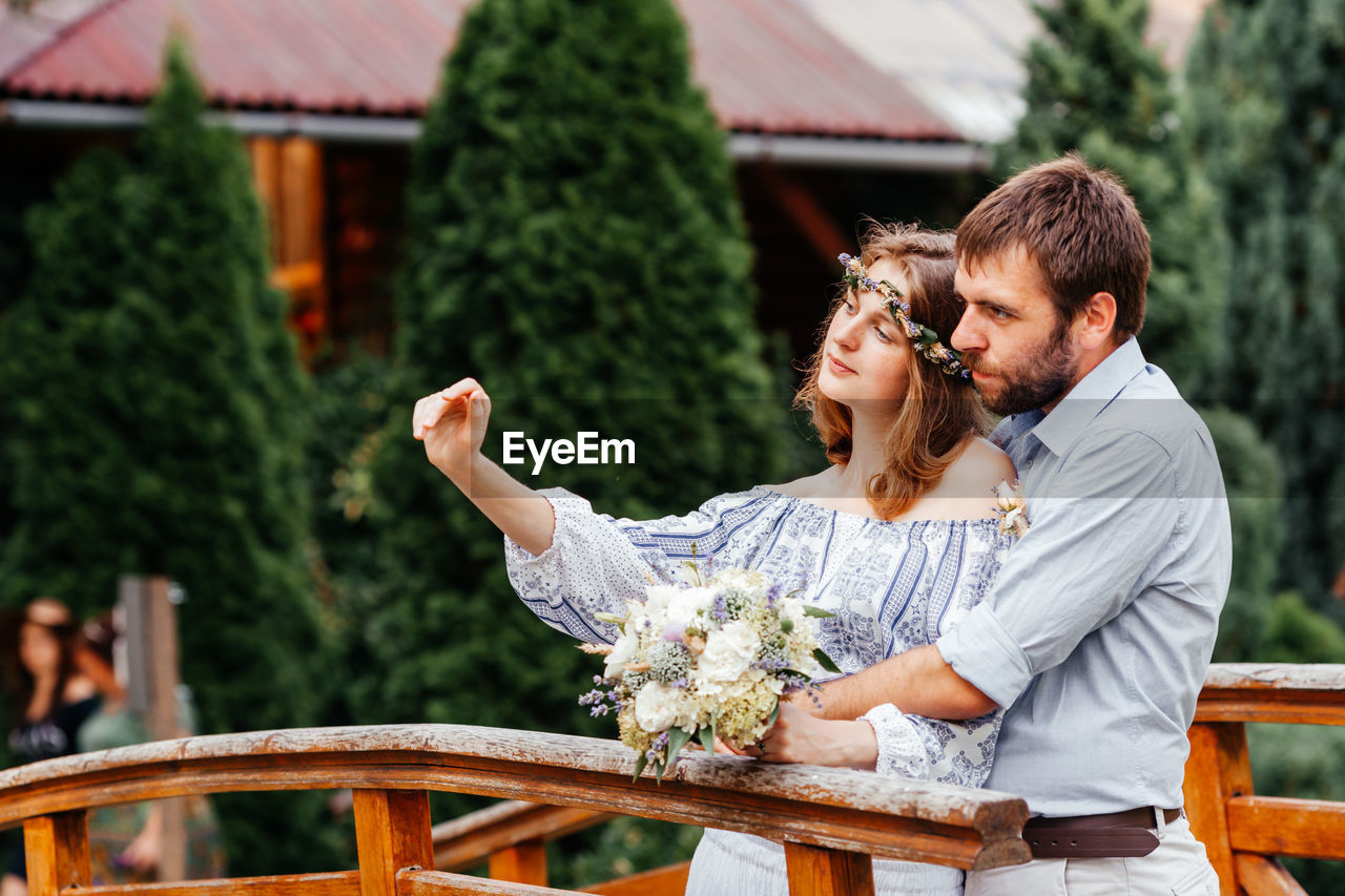 Couple holding bouquet standing outdoors