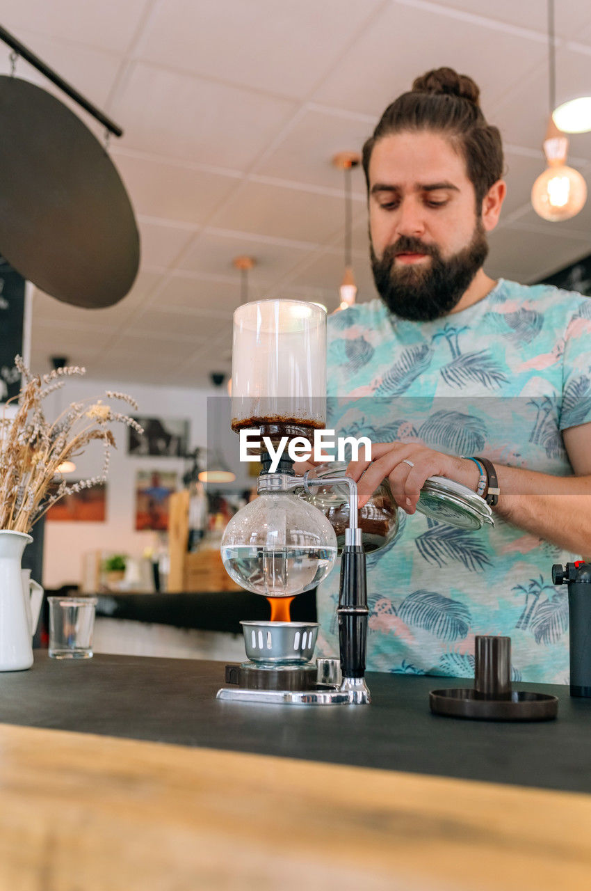 Barista skillfully preparing a specialty coffee in japanese siphon coffee maker with precision