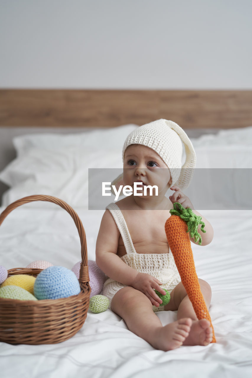 Cute girl with carrot sitting on bed