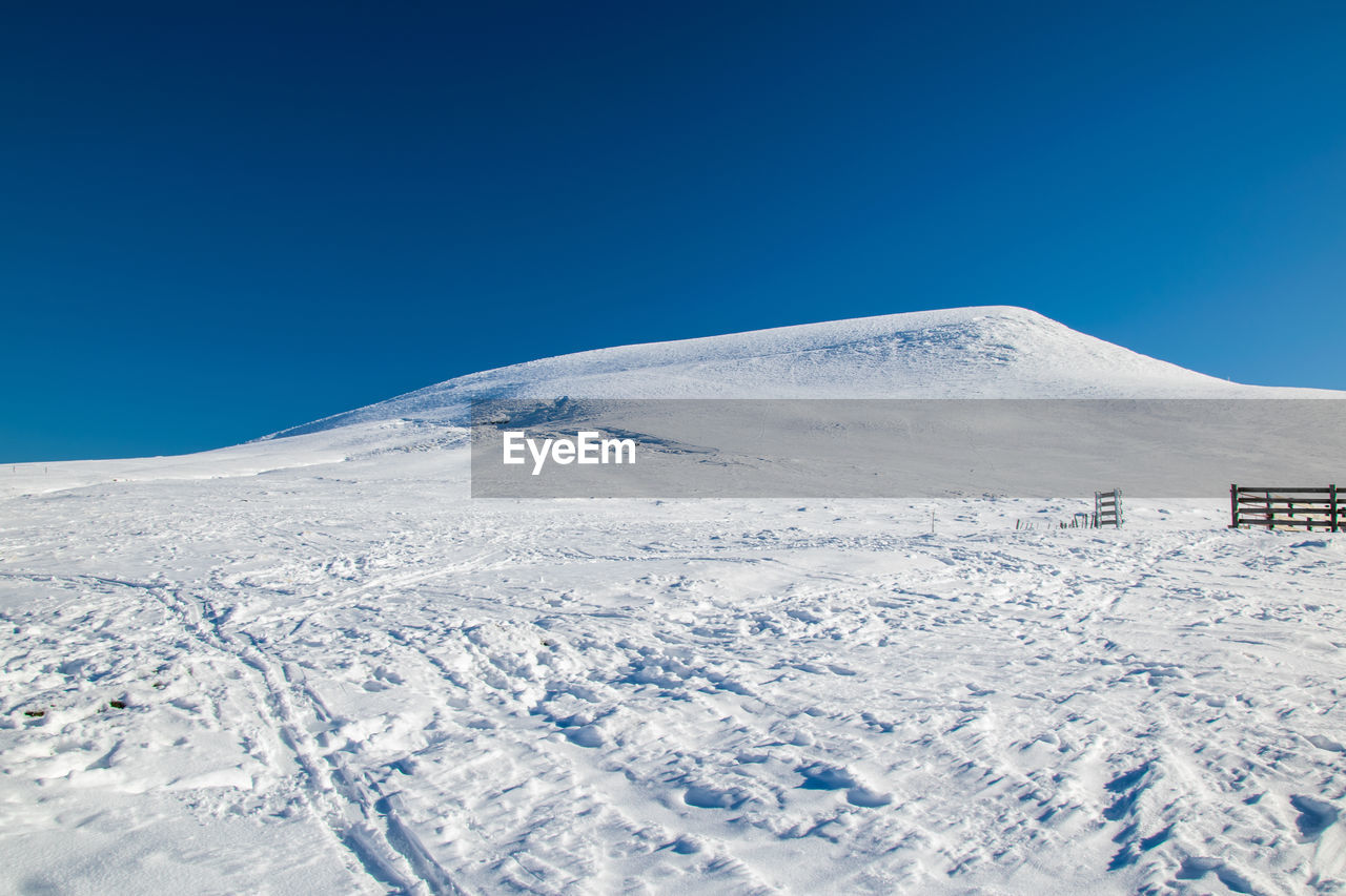 Scenic view of snowcapped mountains against clear blue sky