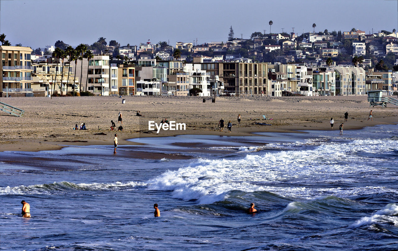 PEOPLE ENJOYING ON BEACH AGAINST CLEAR SKY