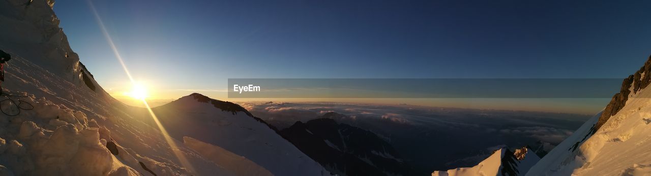 PANORAMIC SHOT OF SNOWCAPPED MOUNTAINS AGAINST SKY DURING SUNSET