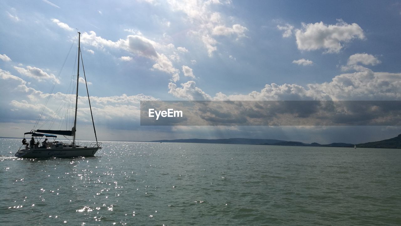 Boat sailing in sea against cloudy sky