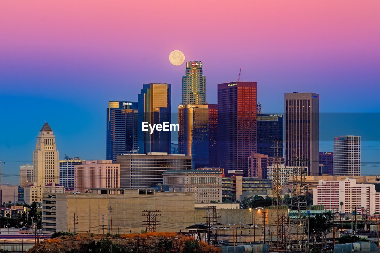 Modern skyscrapers in city against clear sky at dusk