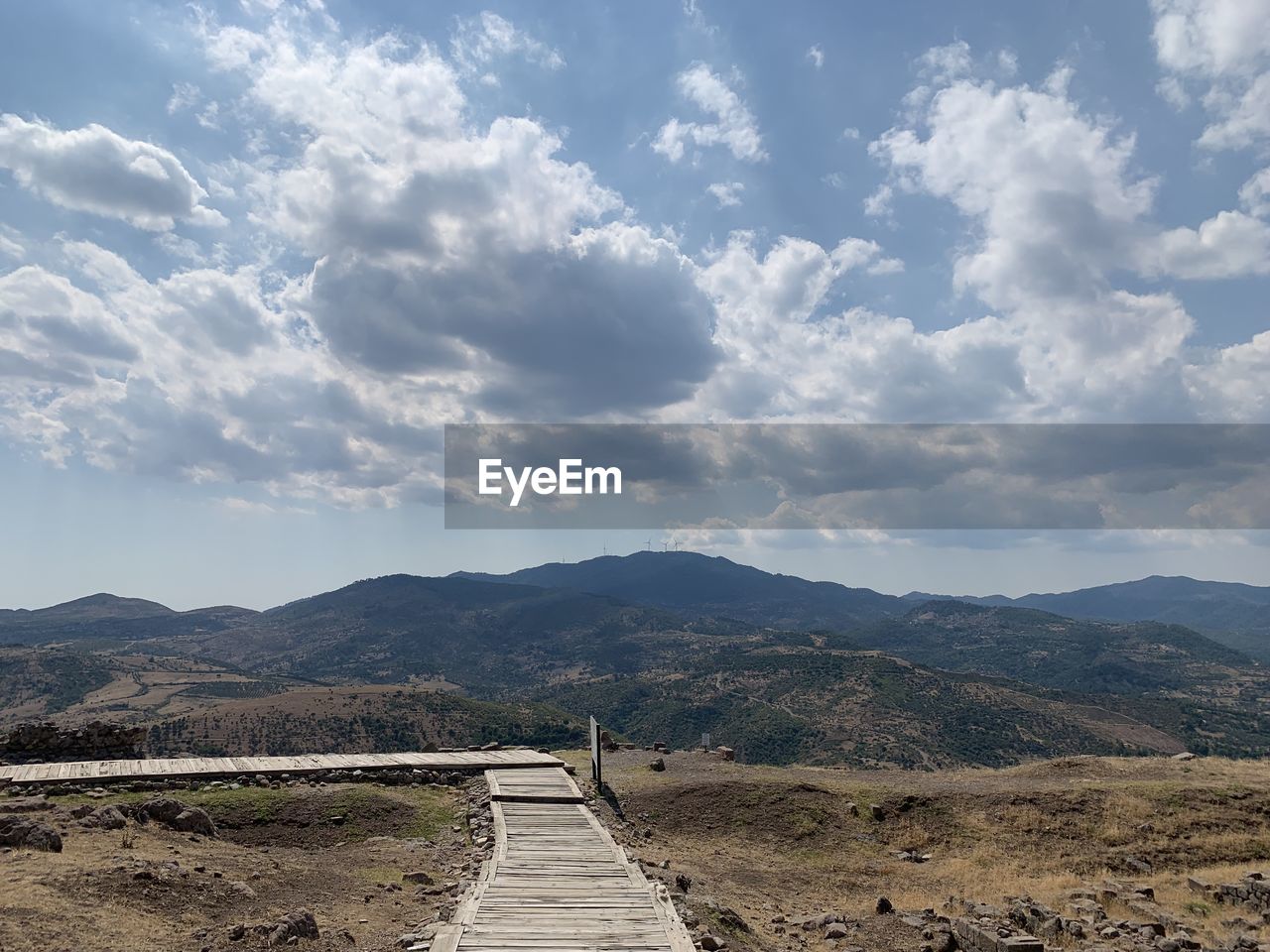 Footpath leading towards mountains against sky