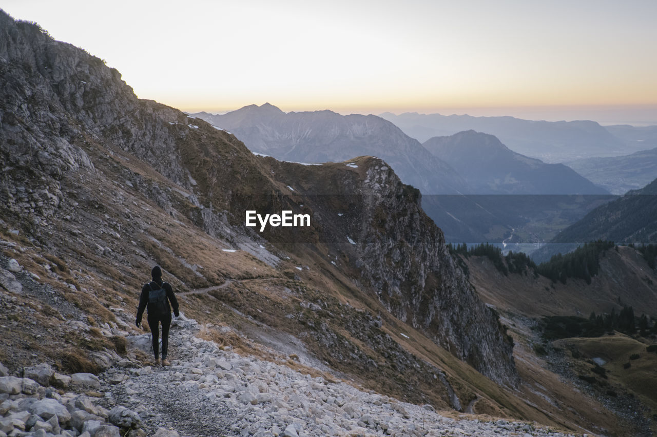 Rear view of woman walking on mountain ridge