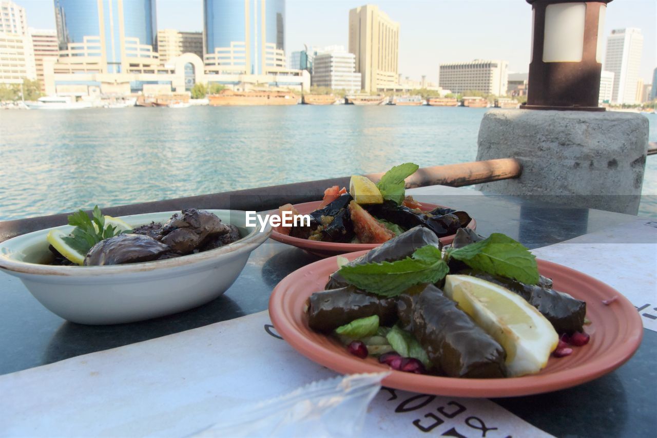 CLOSE-UP OF SALAD IN BOWL ON TABLE AGAINST BUILDINGS