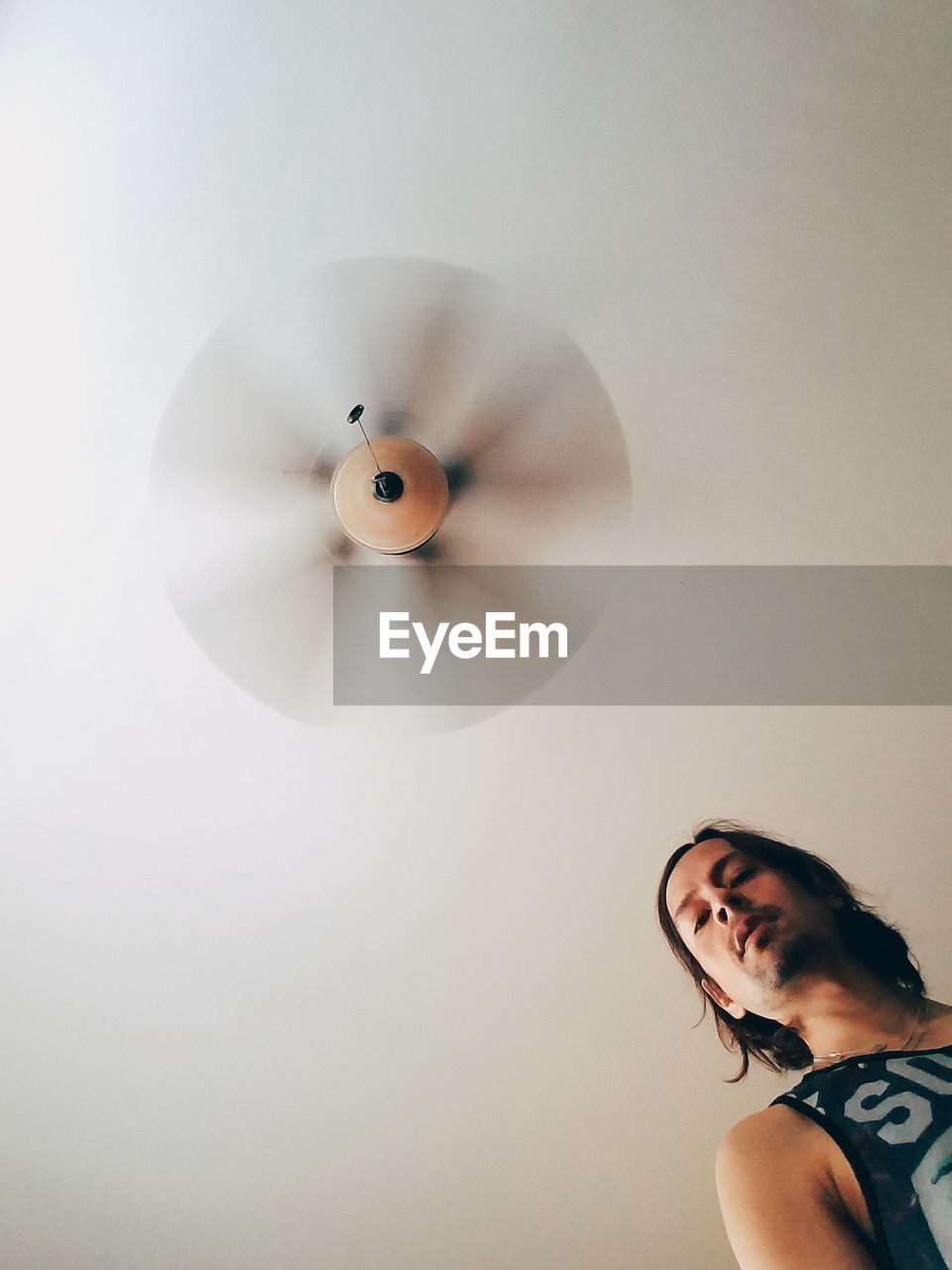 Low angle view of man against spinning ceiling fan at home