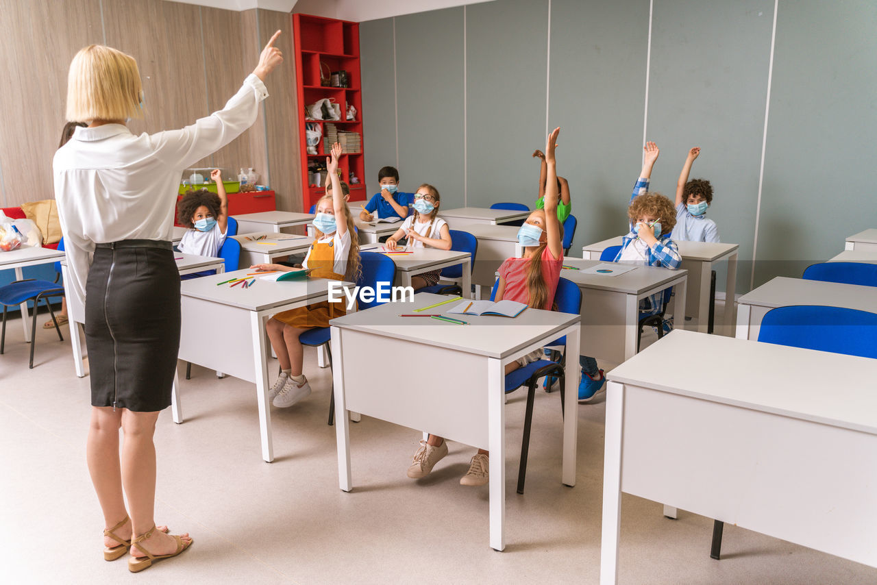 Cute kids wearing mask raising hands at hospital