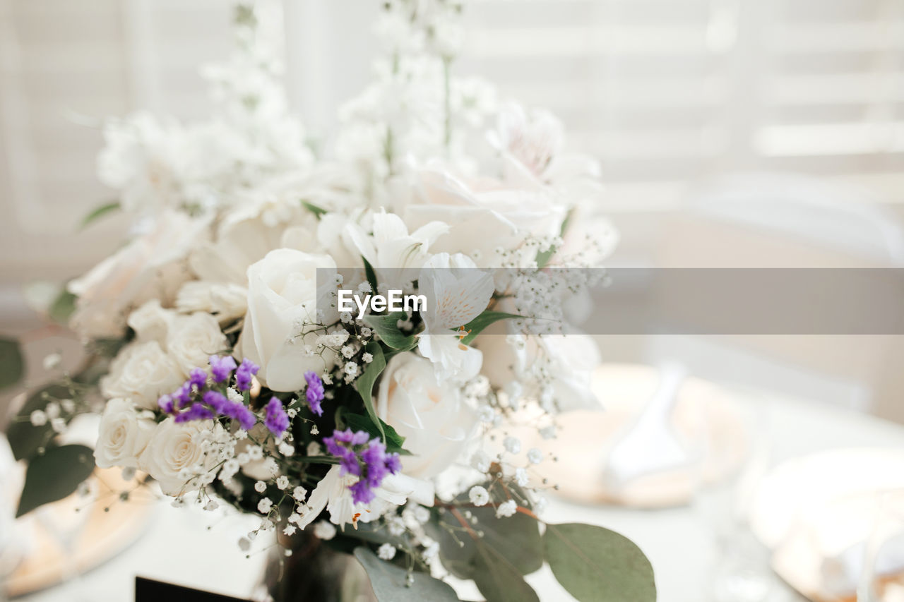 Wedding decor - guest tables with white tableclothes, golden plates, and floral arrangements.