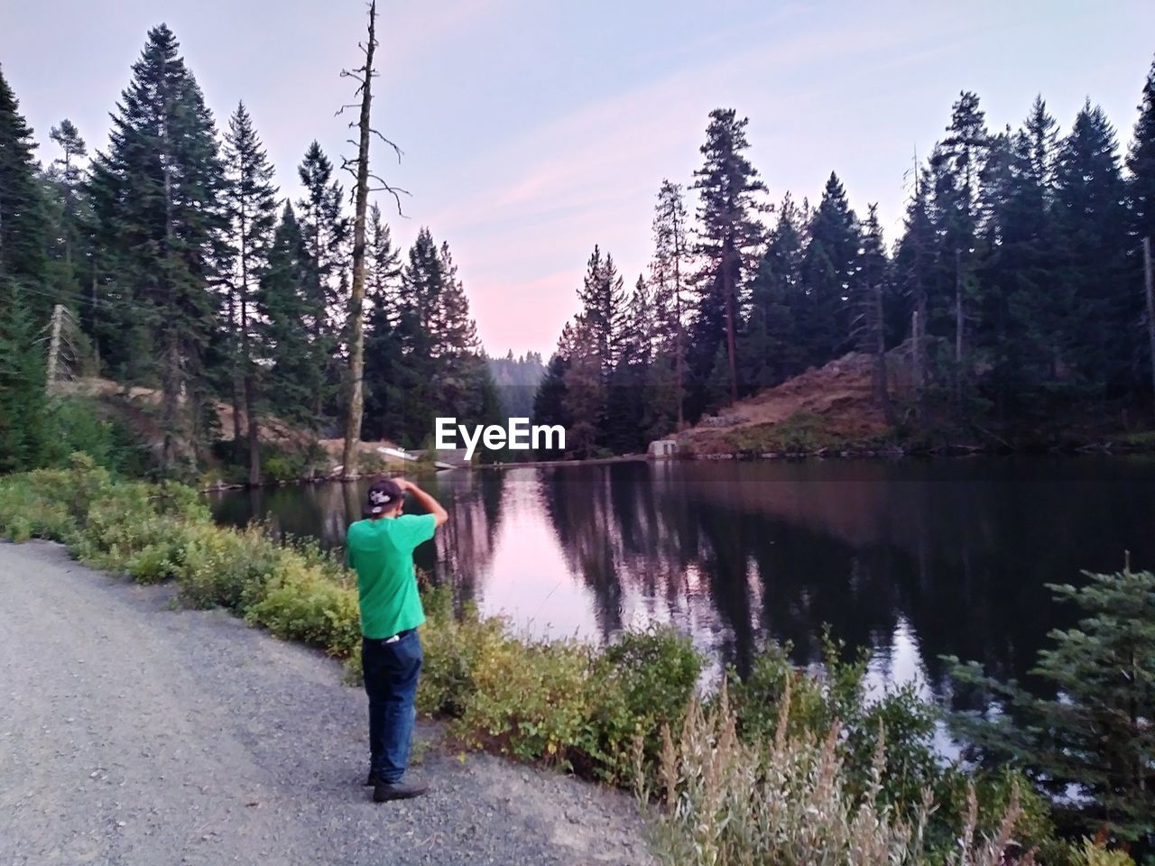 REAR VIEW OF MAN STANDING ON ROAD AGAINST TREES