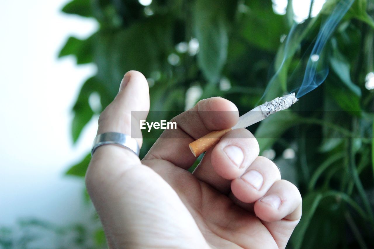Midsection of person holding cigarette