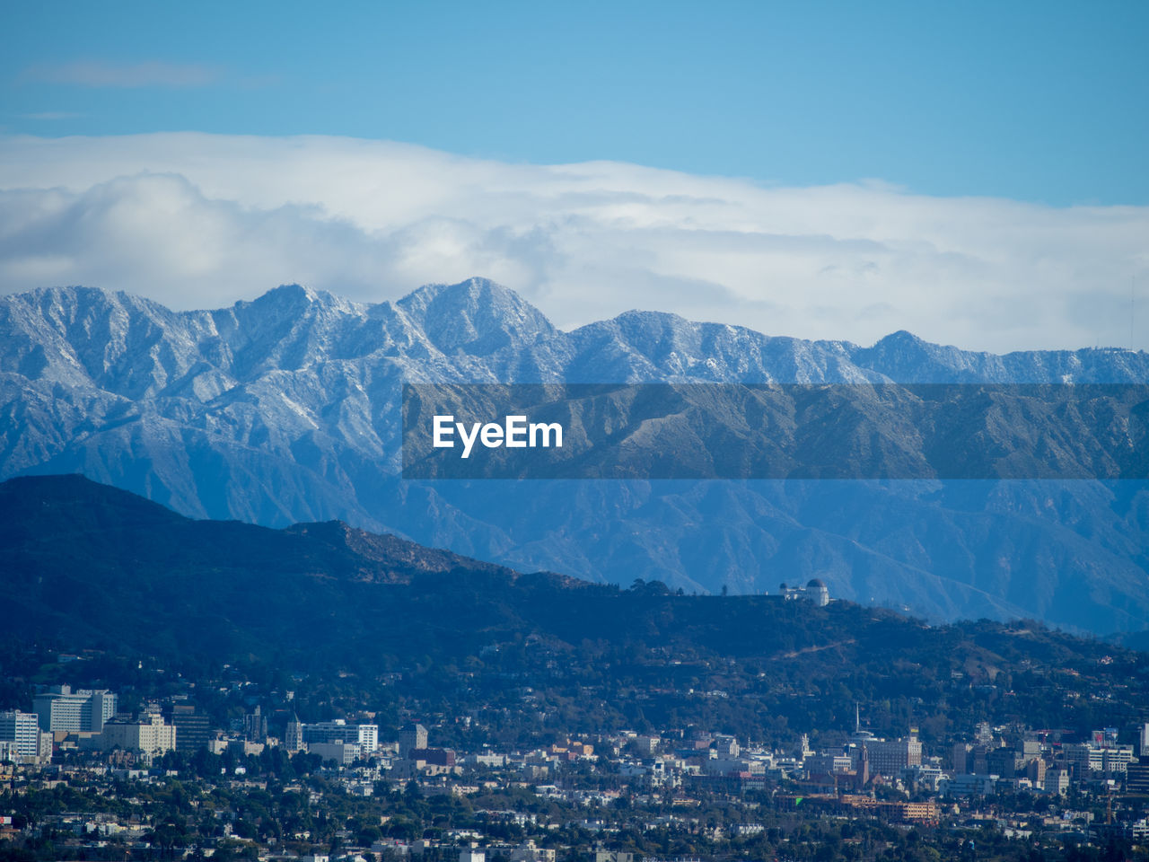 Aerial view of townscape and mountains against sky