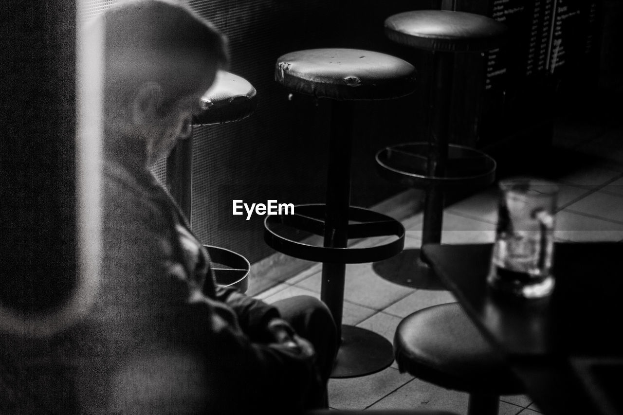 Close-up of man sitting on stool at bar