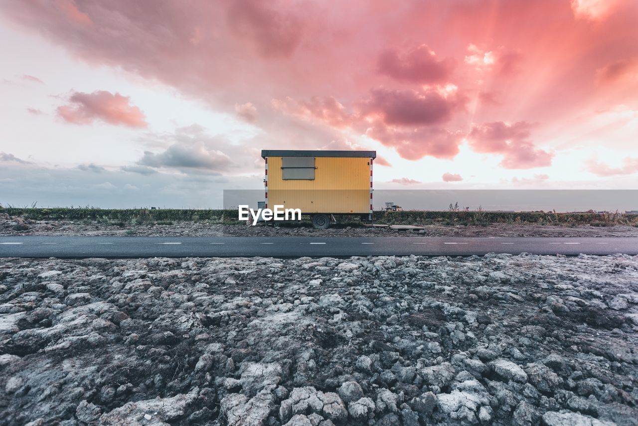 House by road against cloudy sky