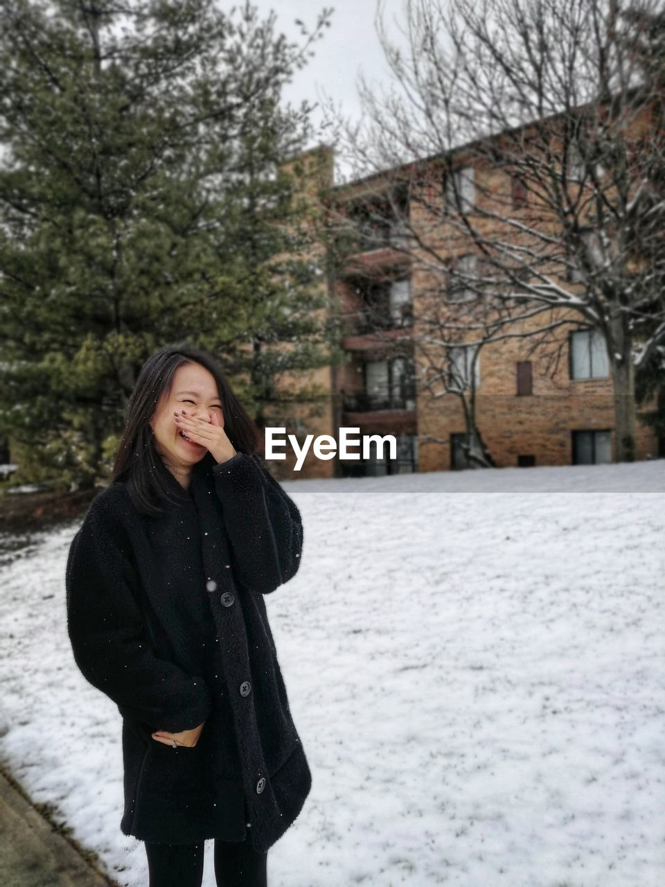 Happy woman standing by snow in city