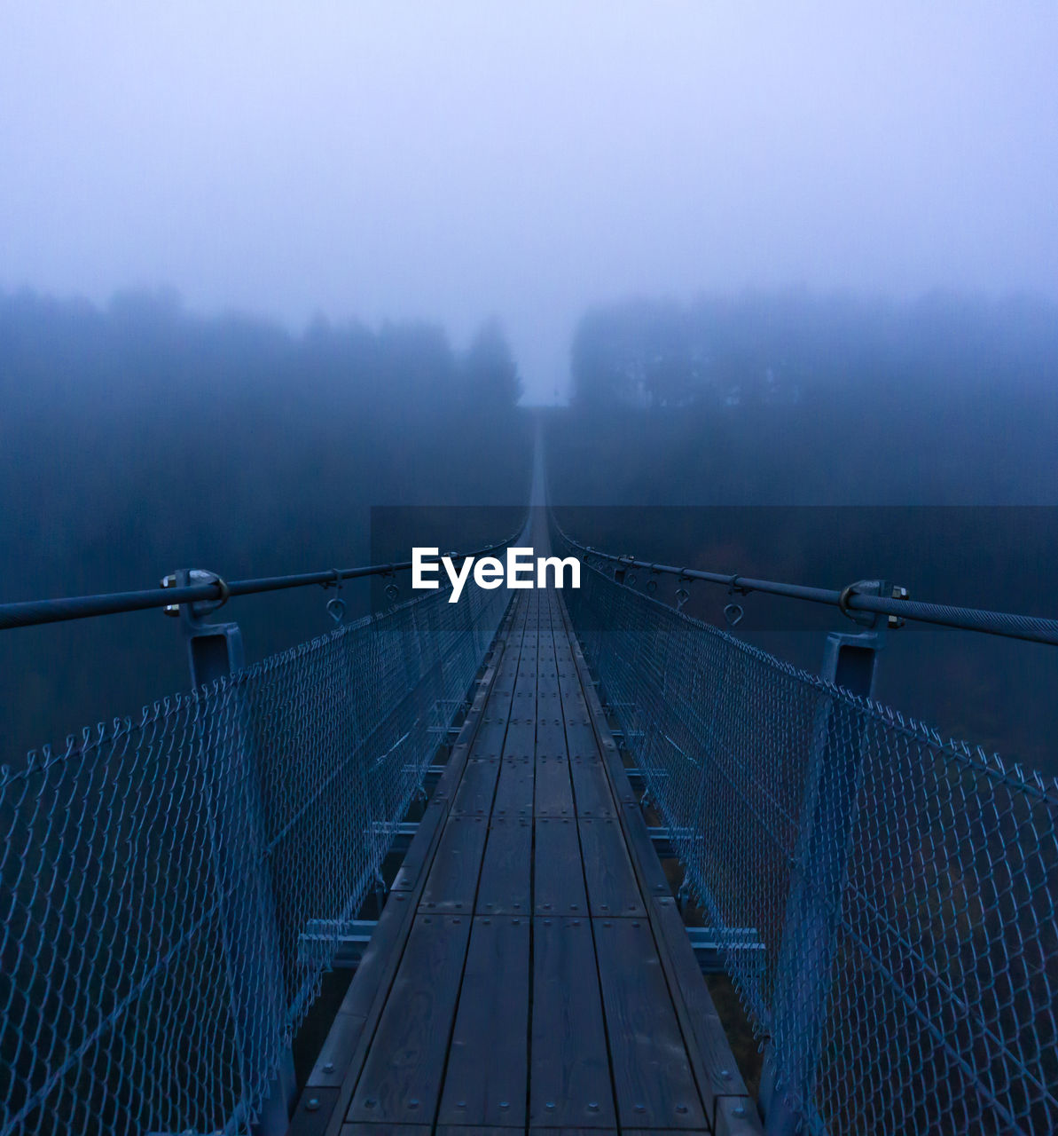 Diminishing perspective of footbridge during foggy weather