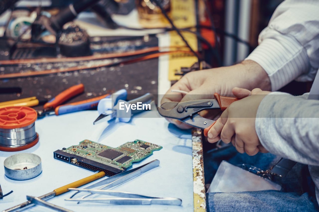 Cropped image of technicians cutting wire indoors