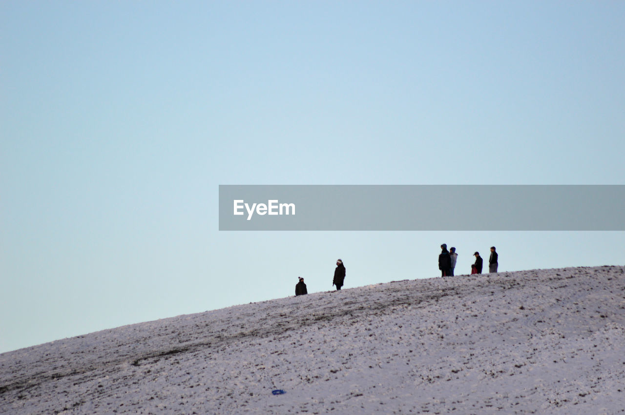 People on mountain against clear sky