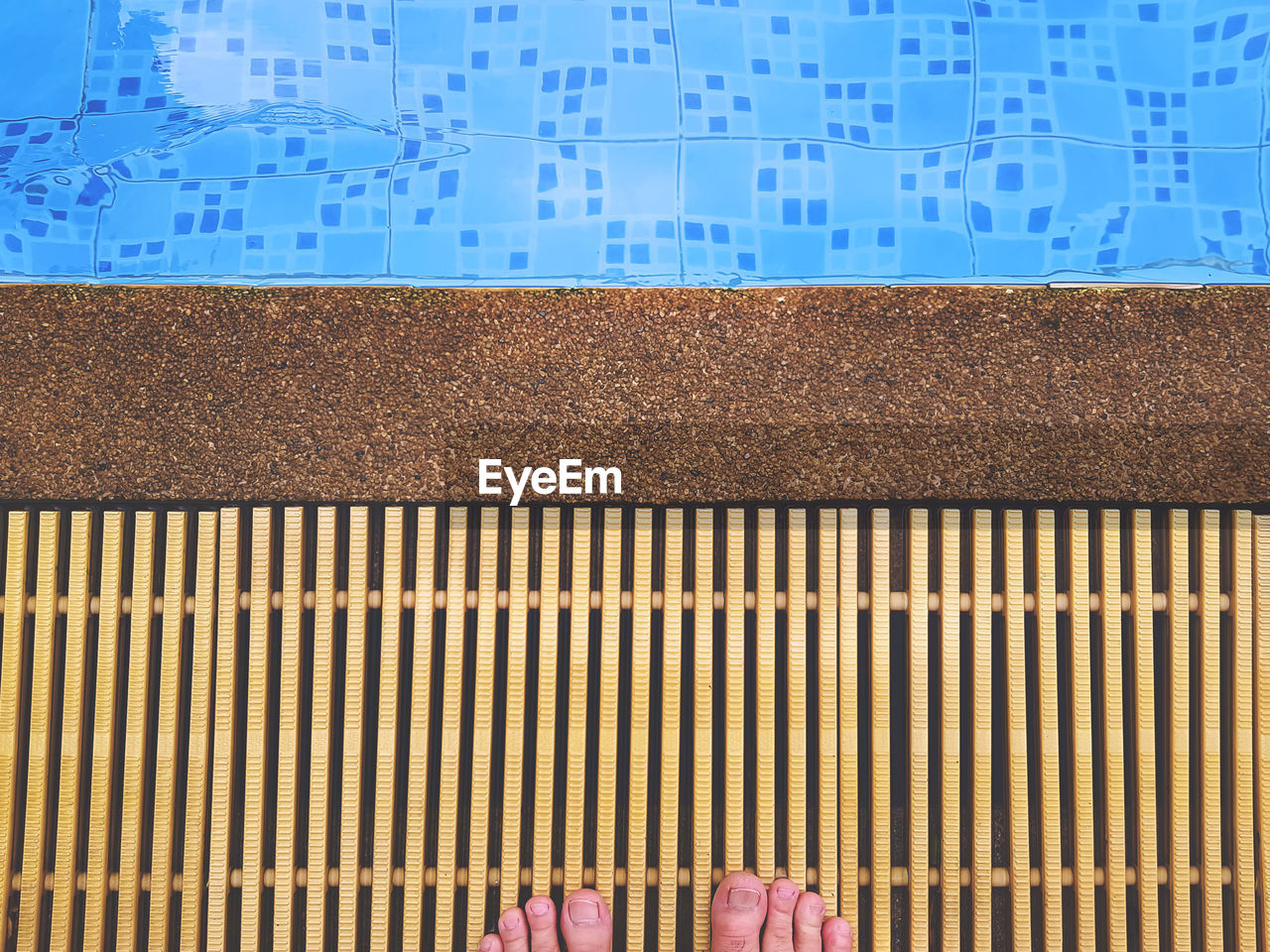 Low section of person standing at poolside