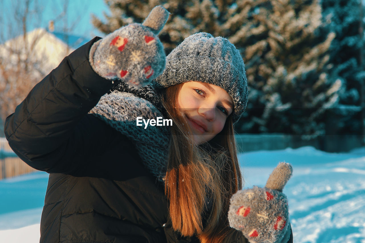 Portrait of woman in warm clothing gesturing thumbs up during winter