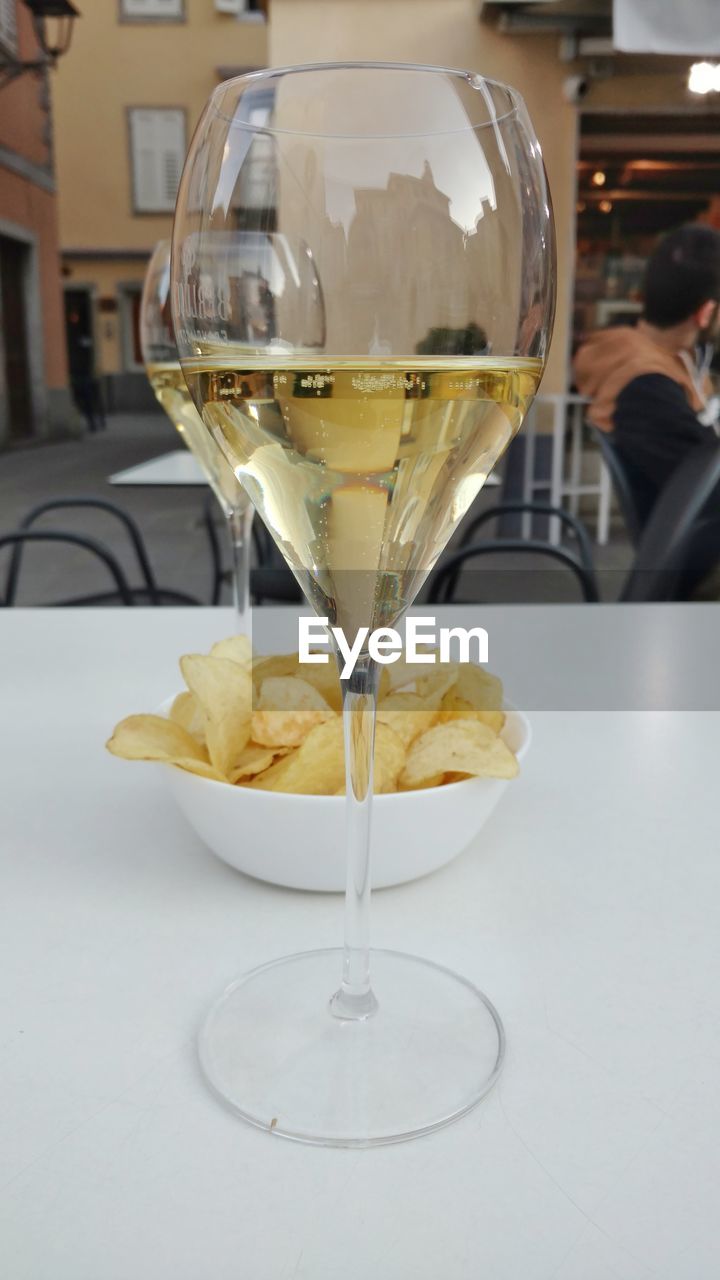 Close-up of alcoholic drink with potato chips on table in restaurant