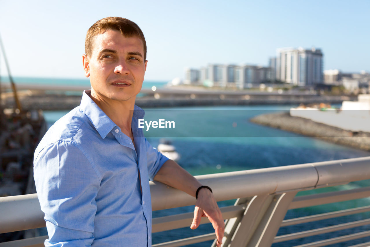 Mature man looking away while standing by railing