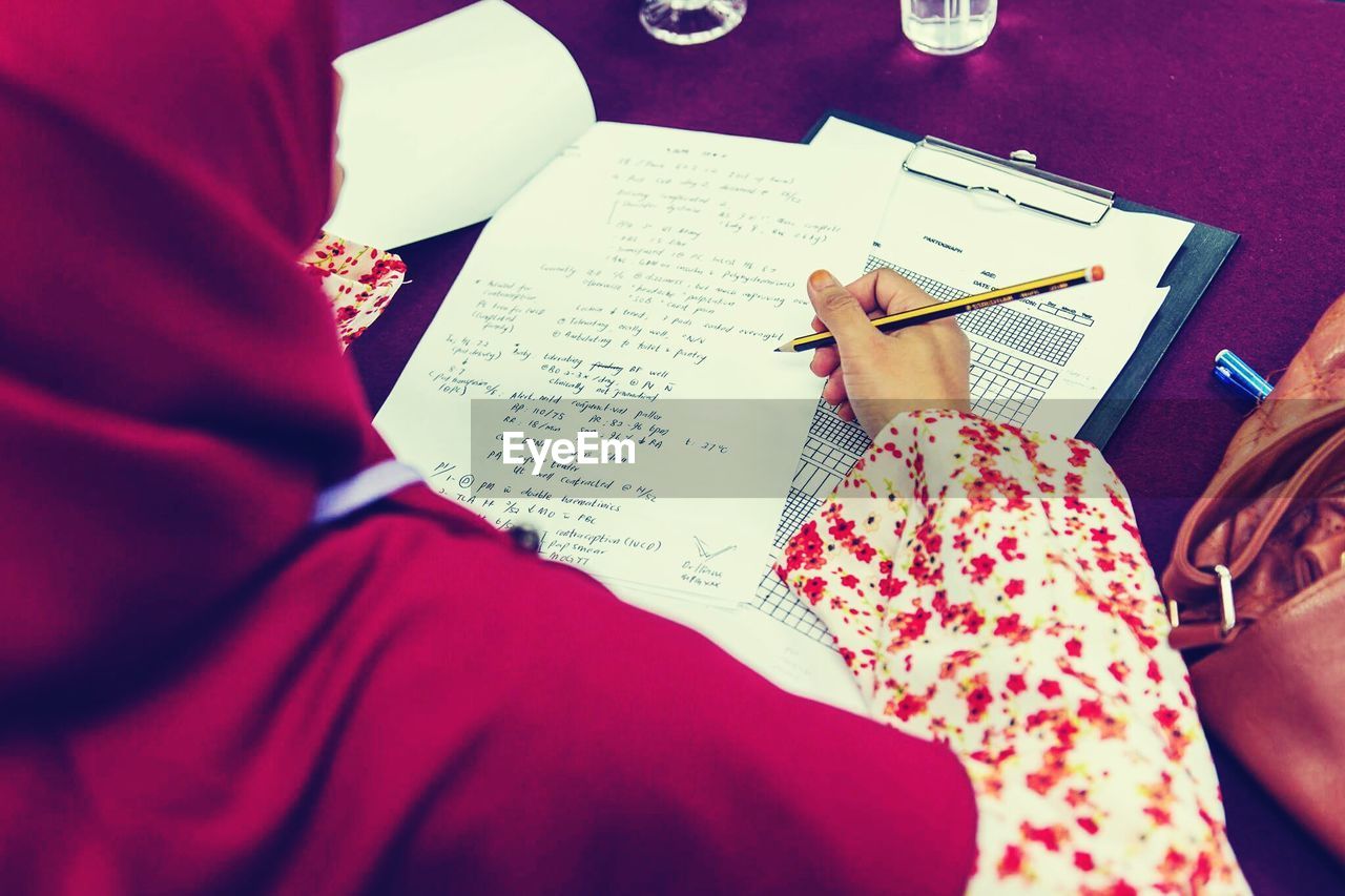 High angle view of woman writing on paper