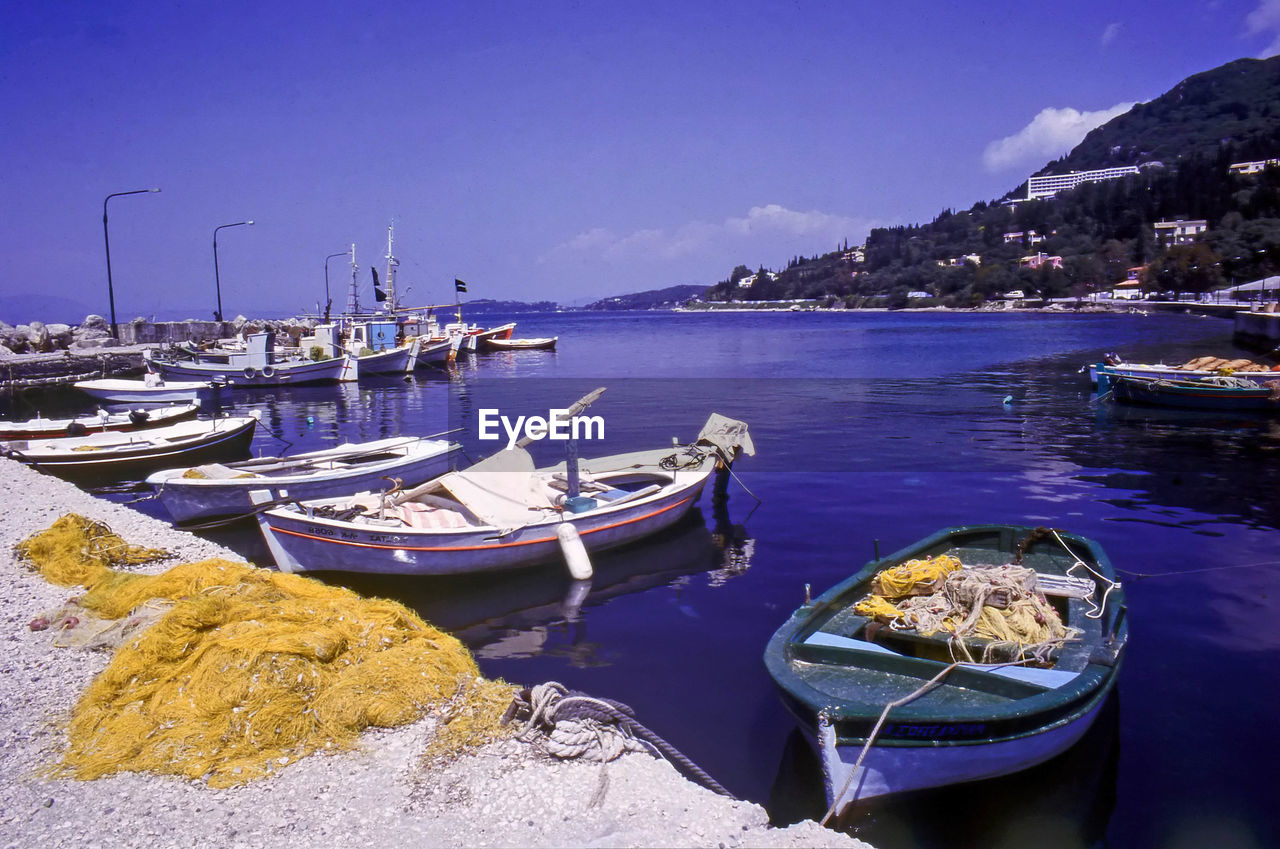 BOATS MOORED ON SEA BY MOUNTAINS AGAINST SKY