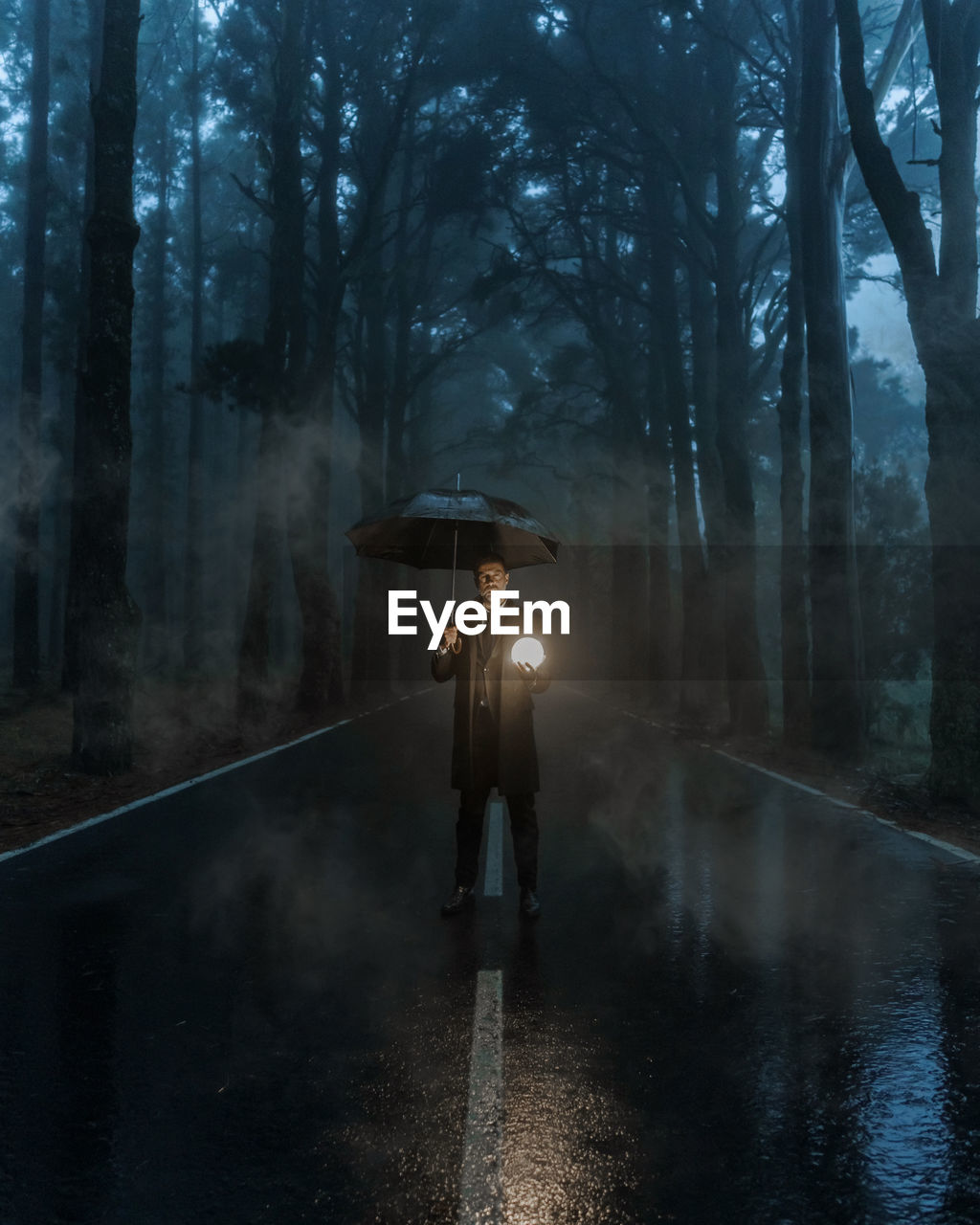 Man standing on wet road in forest during rainy season