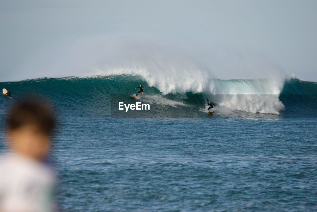 People surfing in sea against sky