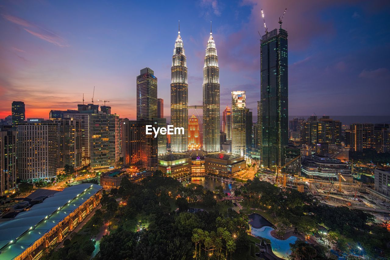 Illuminated buildings in city against sky at dusk