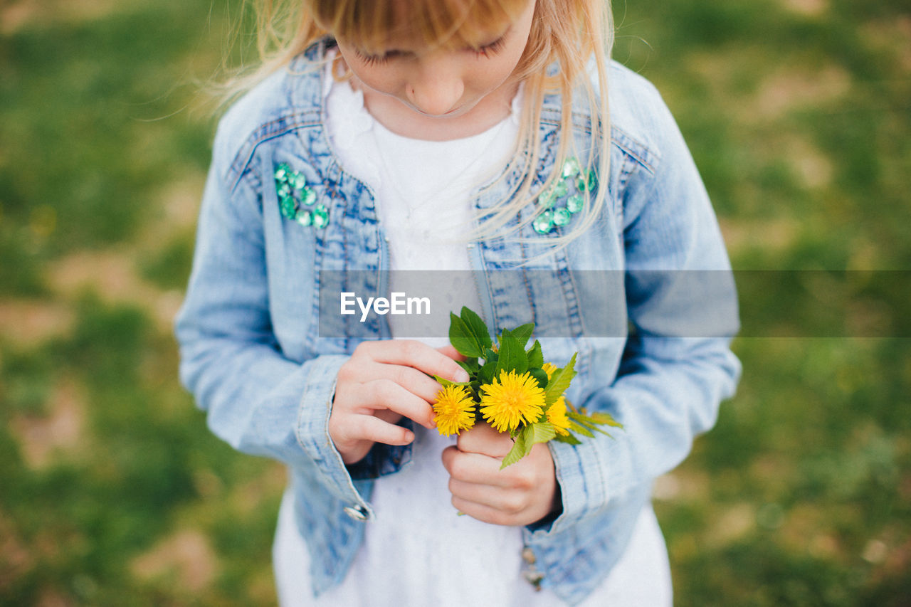 Small girl is holding small girl is holding a bouquet with yellow flowers