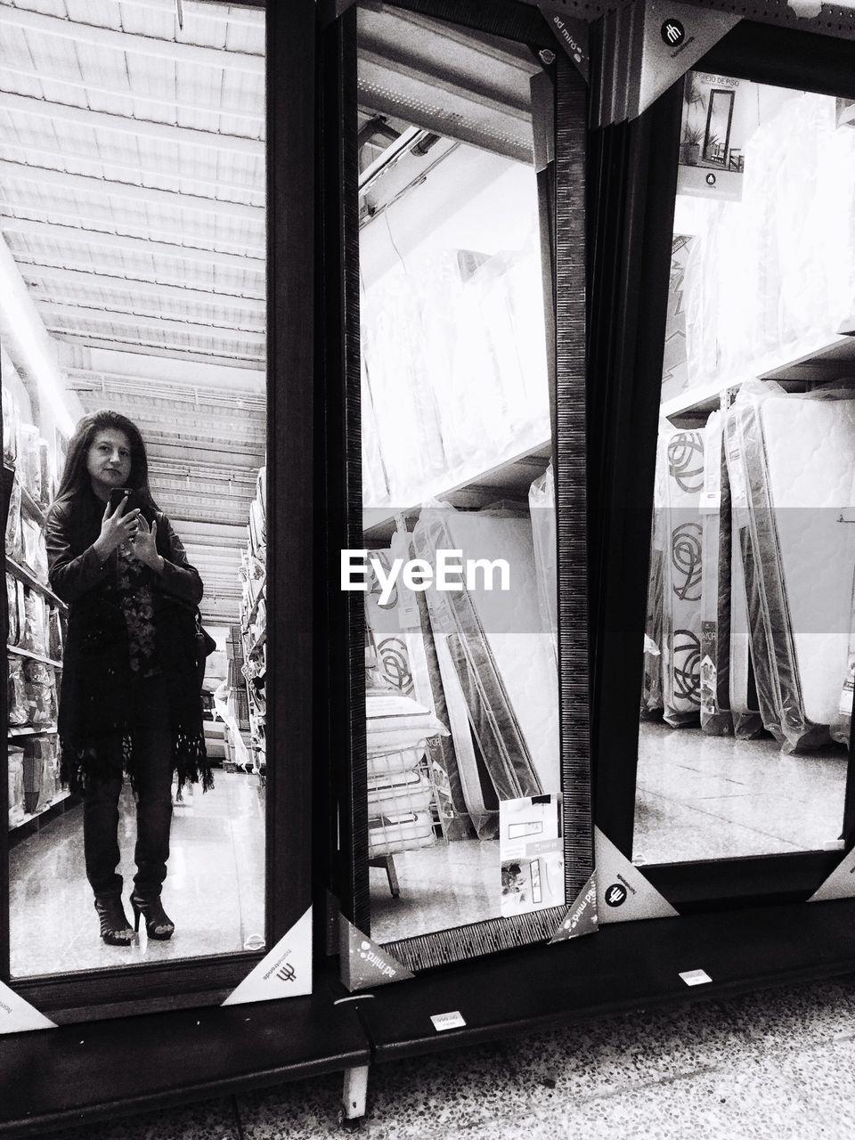 Reflection of woman photographing on mirror in store