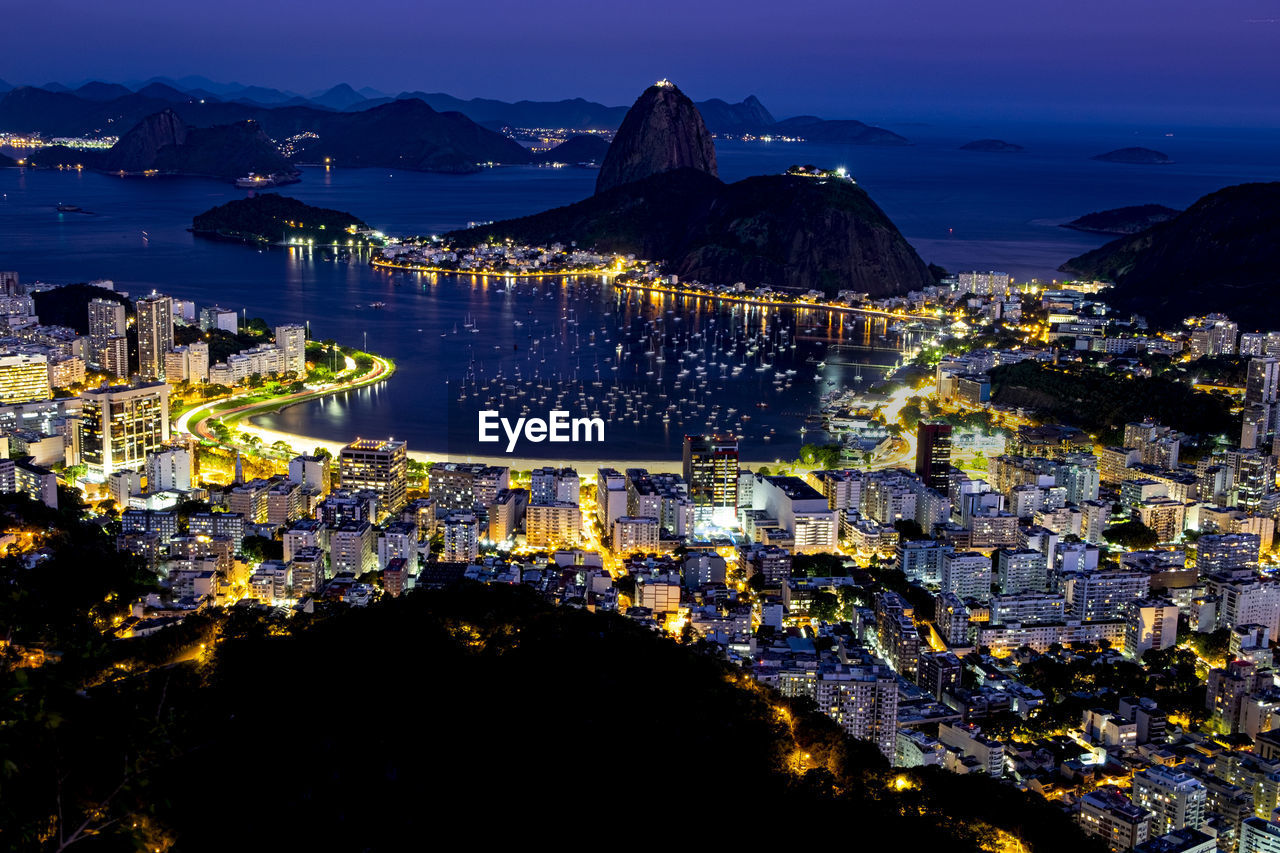 High angle view of illuminated city by sea