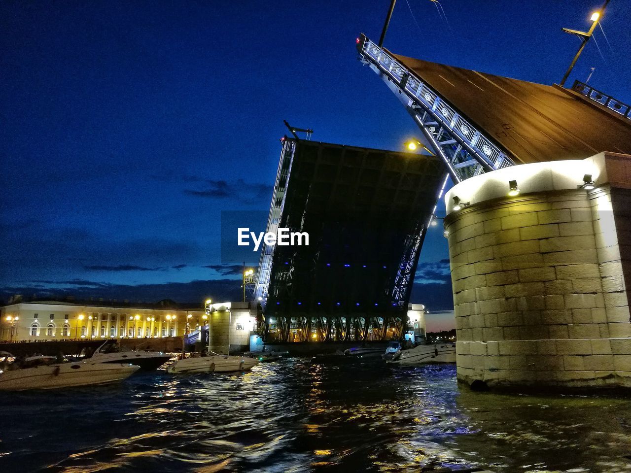 Illuminated bridge over sea against sky at night