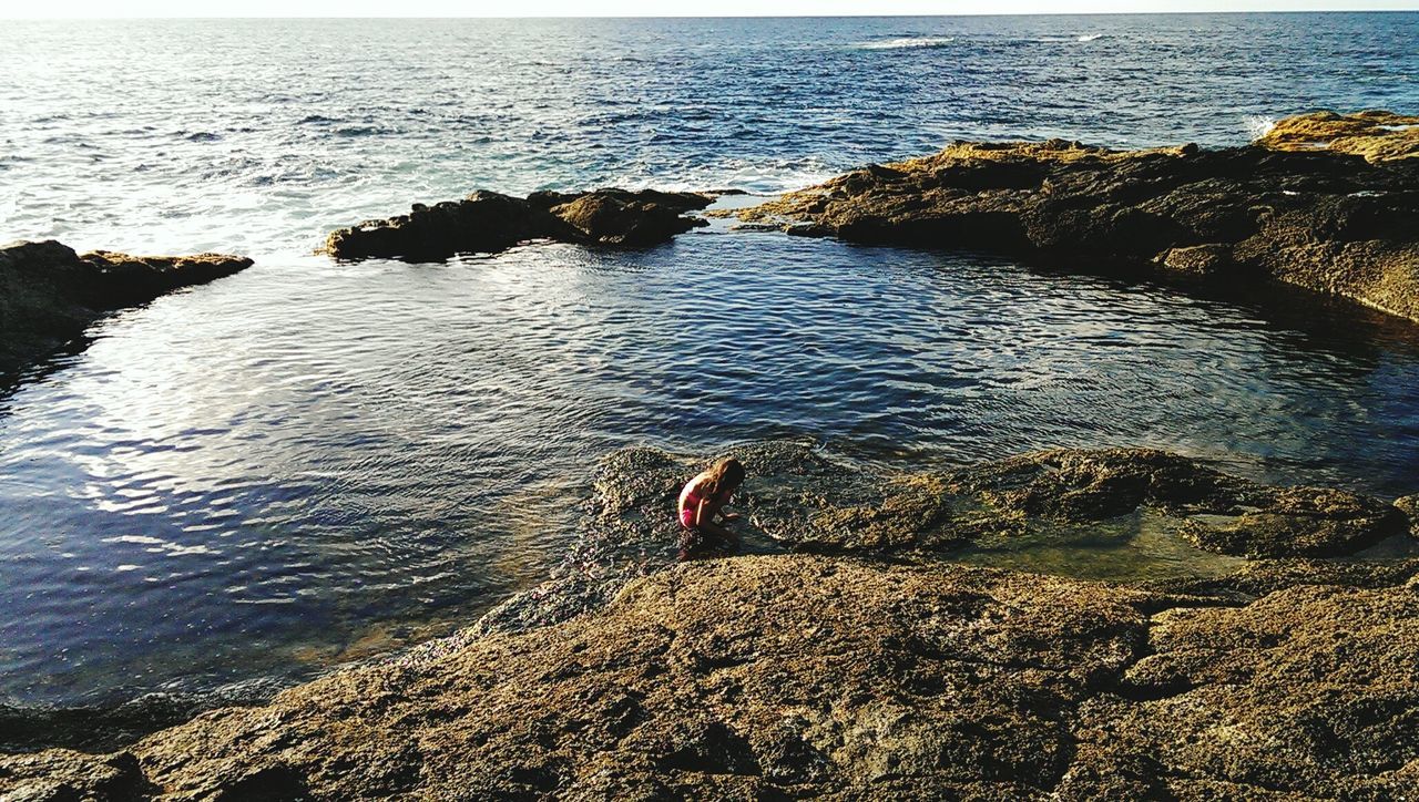 High angle view of girl crouching at seaside