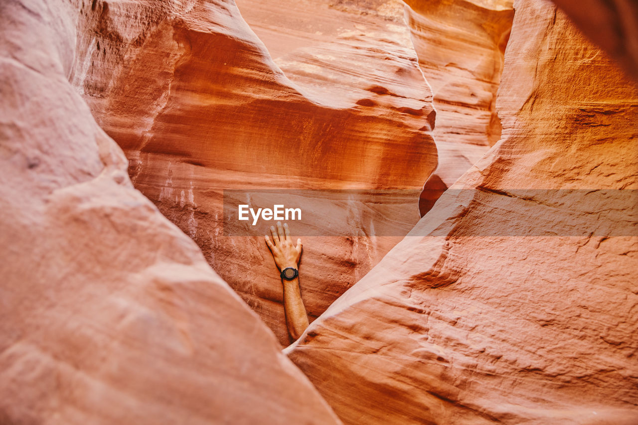 Hand with fitness watch against slot canyon wall in escalante, utah.