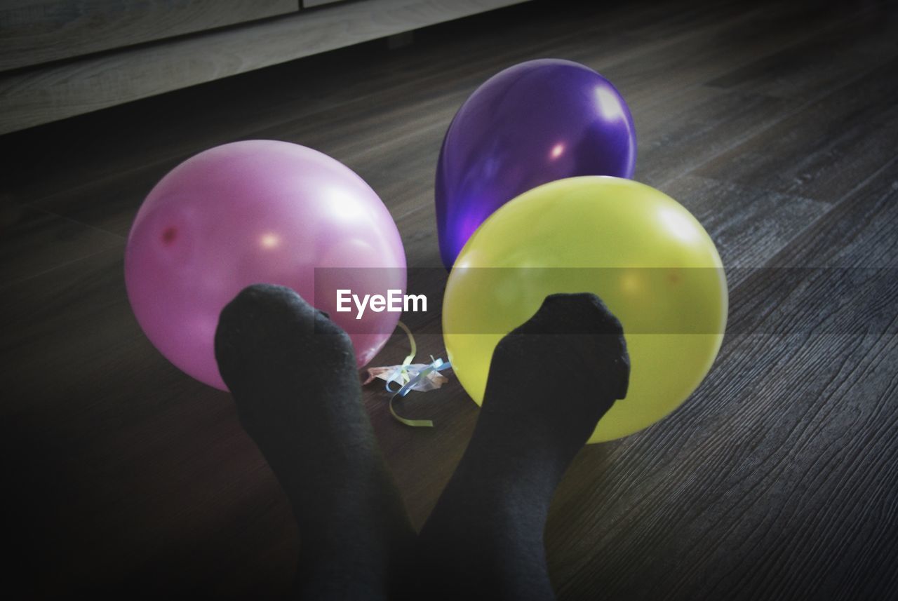 Low section of person wearing socks by balloons on floor