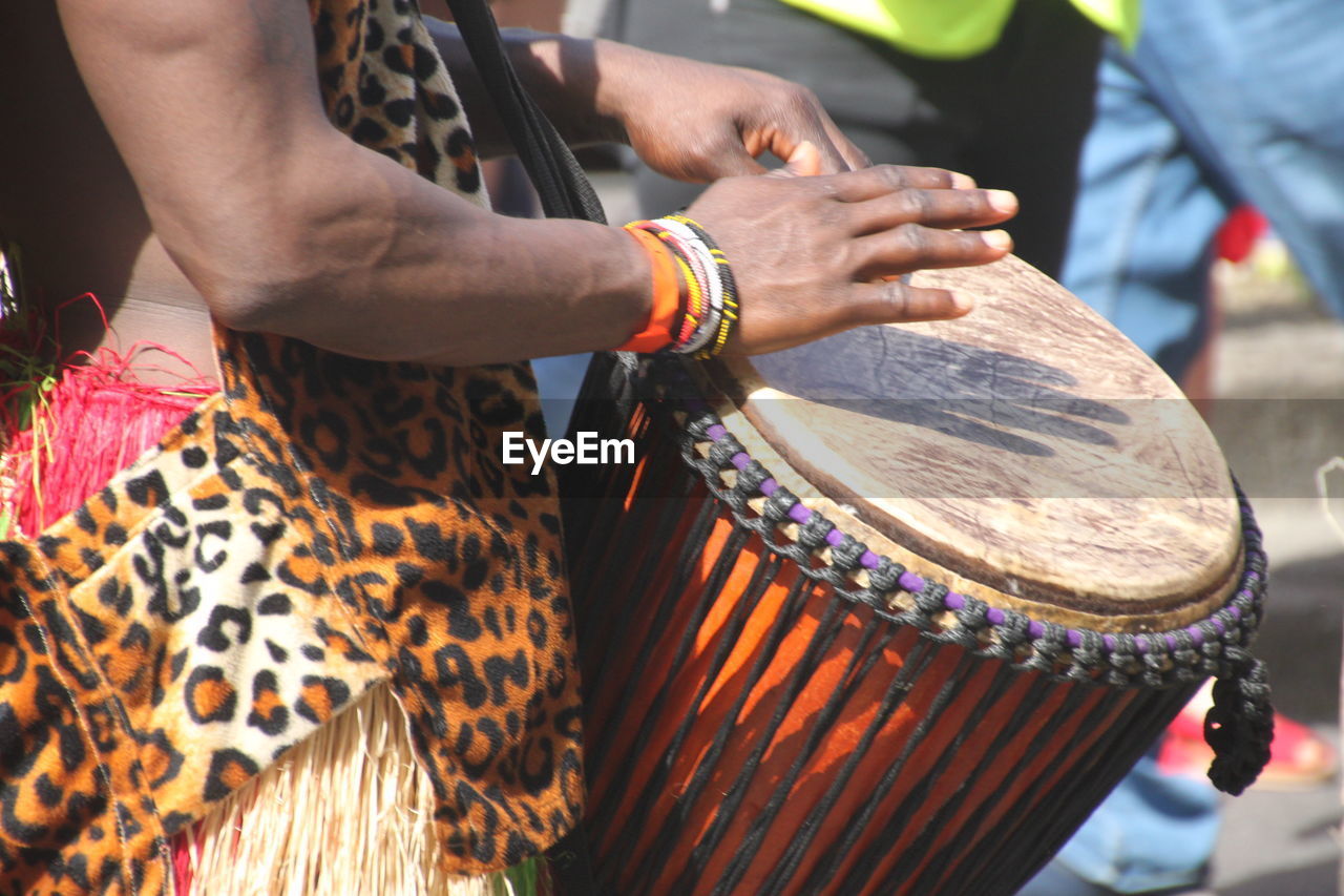 Midsection of man playing drum